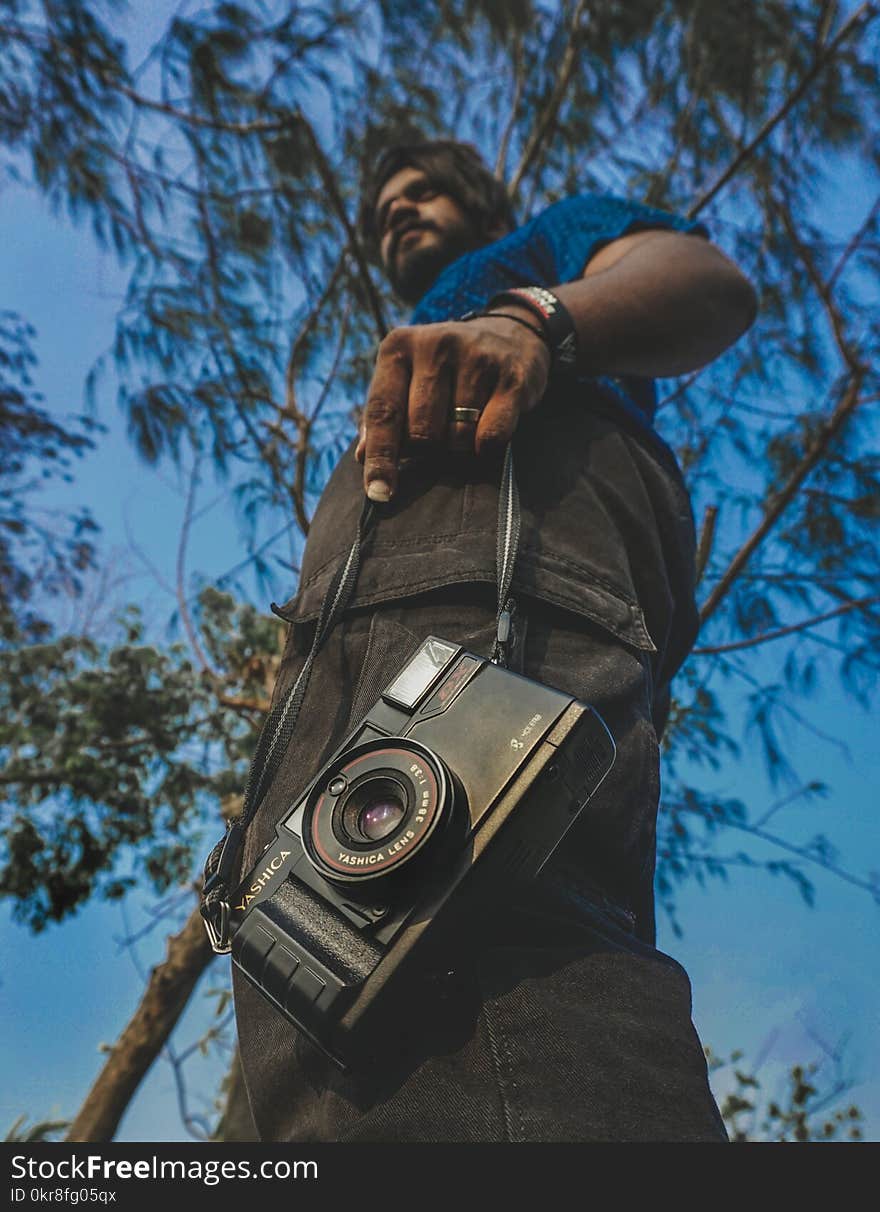 Worm&#x27;s View of Man Holding Camera Under Blue Calm Sky