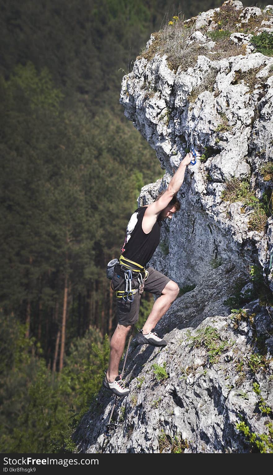 Man Wearing Black Tank Top and Brown Shorts Climbing Rock