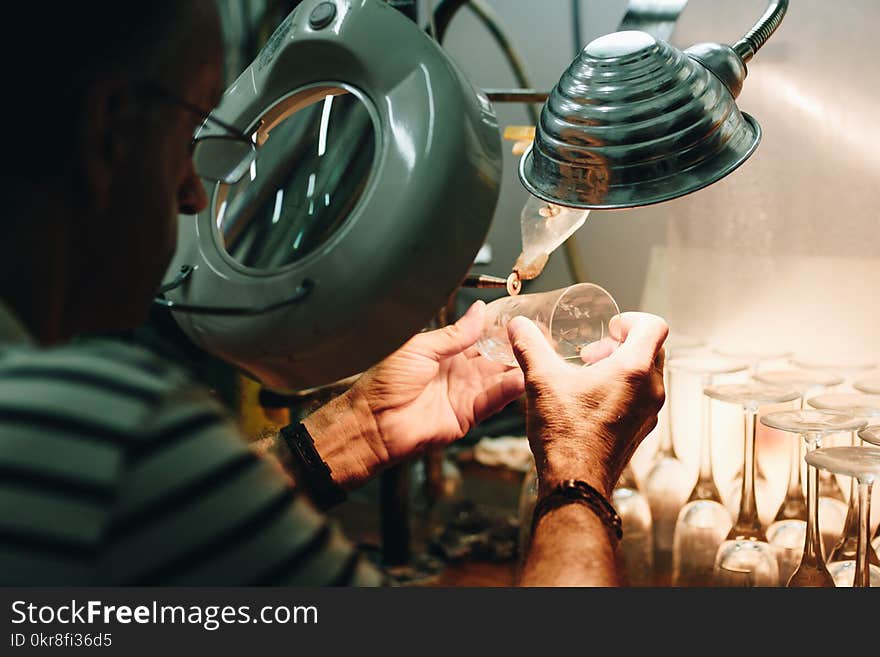 Man in White and Black Stripes Top While Making Drinking Glasses Using Grey Machine