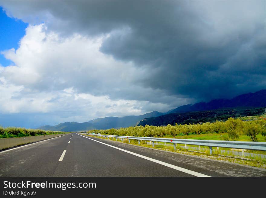 Photo of Road Near Green Leaf Trees Under Dark Clouds at Daytime