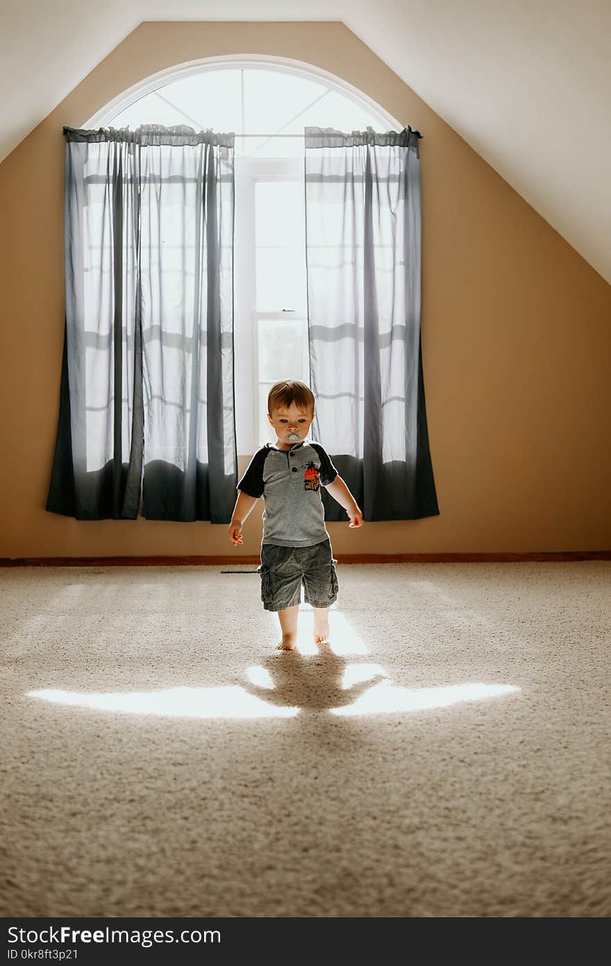 Boy Wearing Gray T-shirt and Gray Cargo Shorts Inside White Painted Wall Room