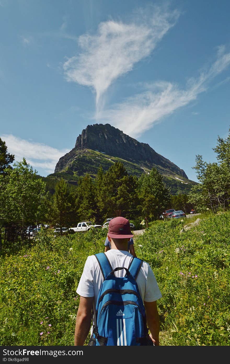 Man Wearing Blue Backpack Walking Between Plants