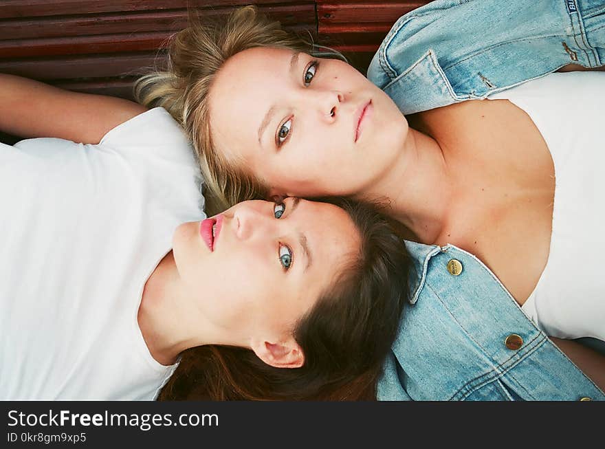 Two Woman Lying on Brown Surface in High Angle Photo