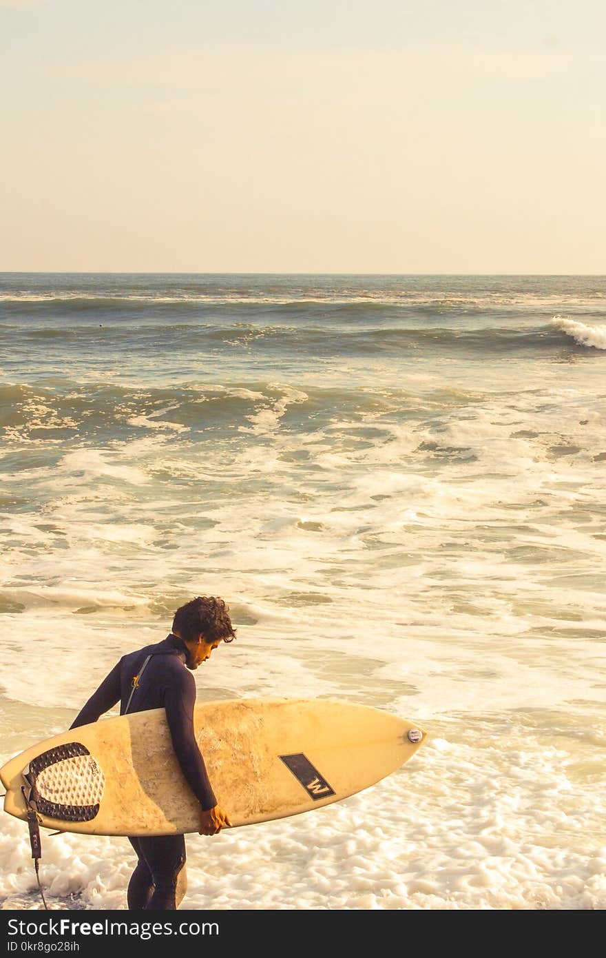 Man Carrying Surfboard Near Shoreline