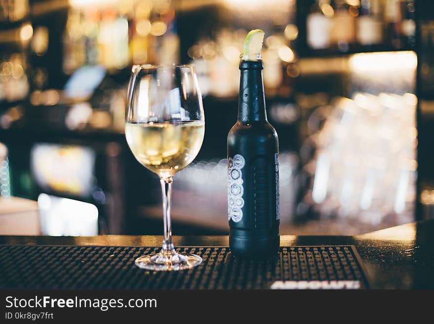 Black Bottle Beside Long-stem Wine Glass on Table