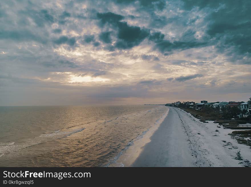 Wide Angle Photo of Shore Under Cloudy Sky