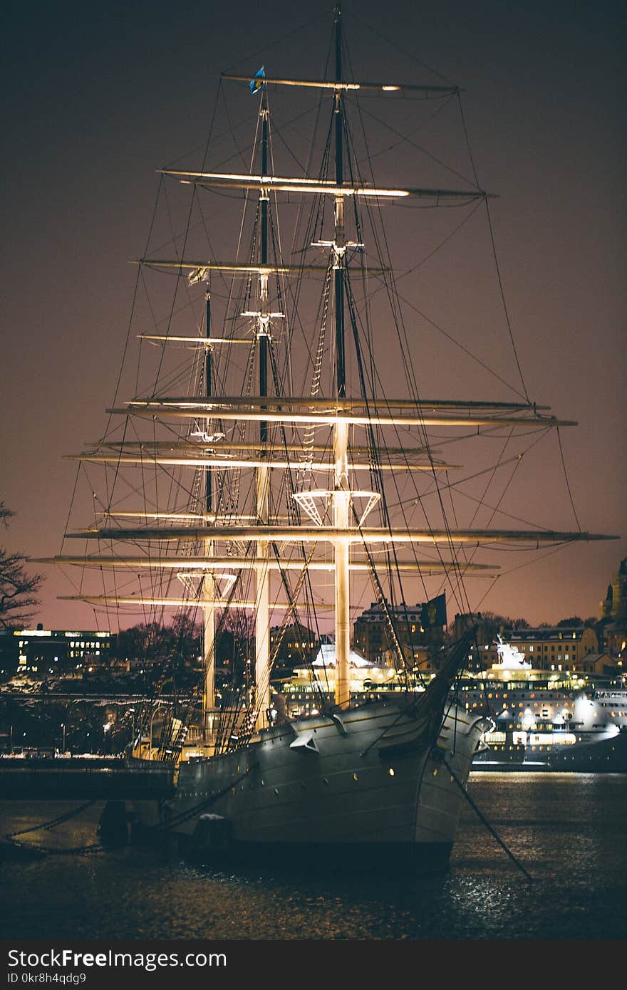 White and Brown Boat With Light Near Buildings at Night