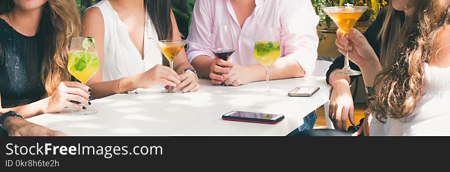 People Drinking Beverage While Sitting Near Table