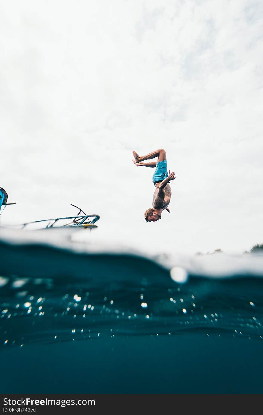 Man Wearing Blue Shorts About to Dive on Body of Water