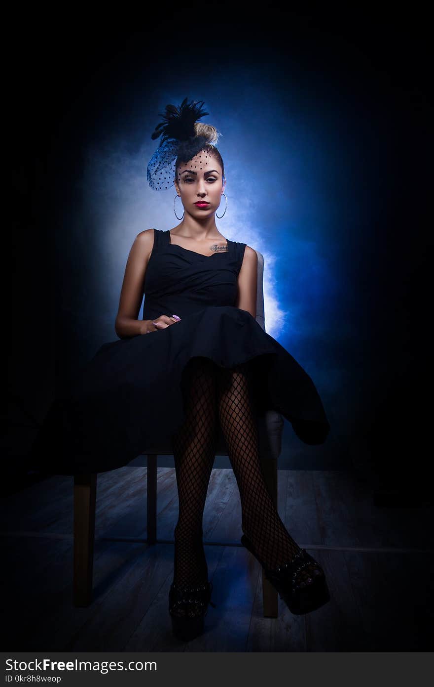 Woman Wearing Tank Dress and Black Floral Head Dress Sitting on Chair