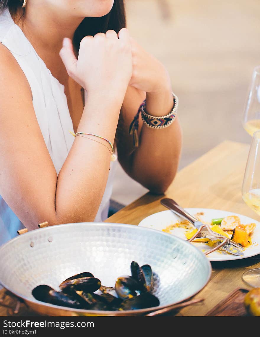 Woman Wearing White Deep V-neck Sleeveless Top Sitting on Chair Near Table