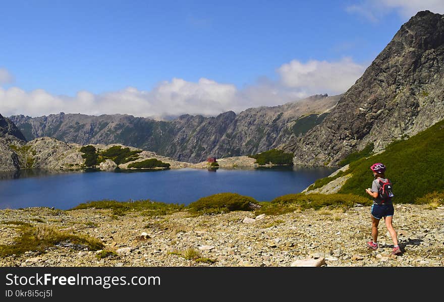 Person Standing Near Lake Under Cloudy Sky