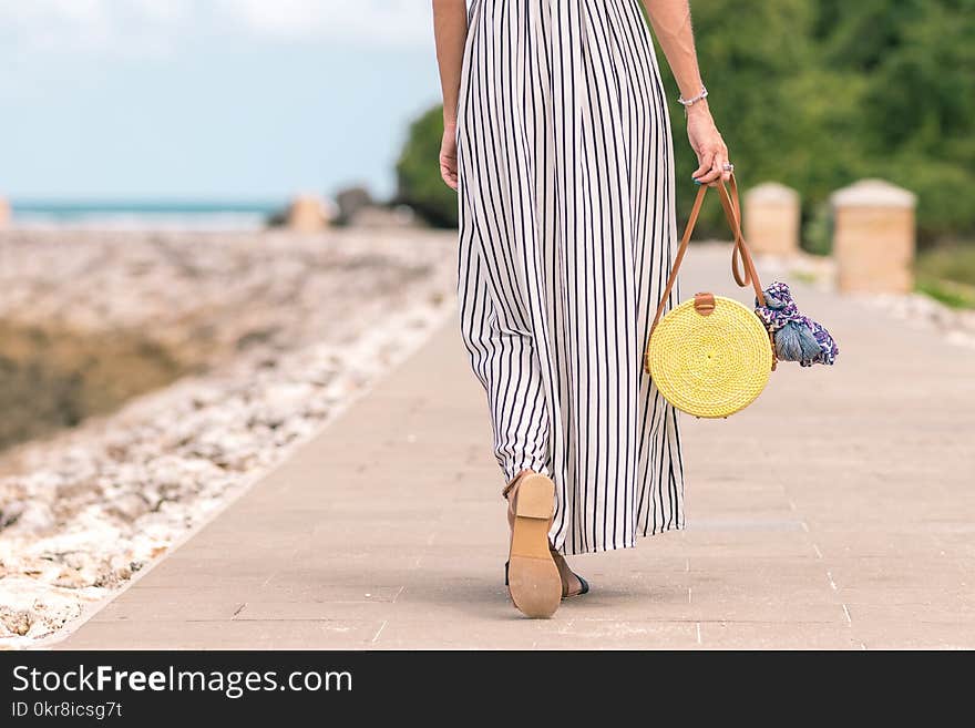 Woman Wearing Black and White Striped Maxi Skirt Holding Brown Bag