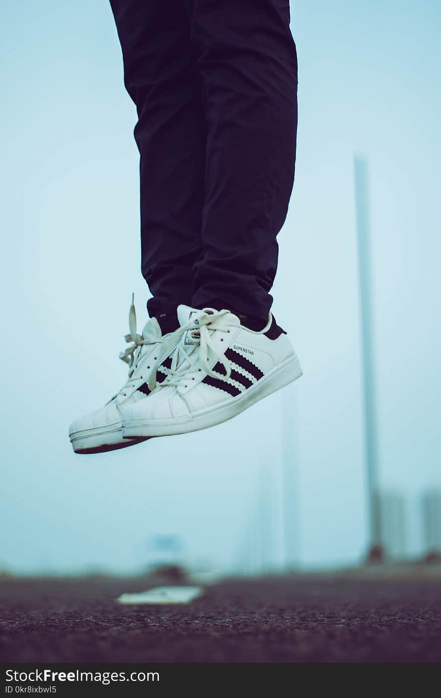 Person Wearing Pair of White Adidas Superstar Shoes