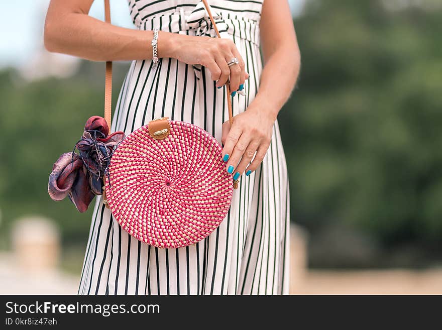 Woman Wearing White and Black Striped Dress Holding Her Red Sling Bag