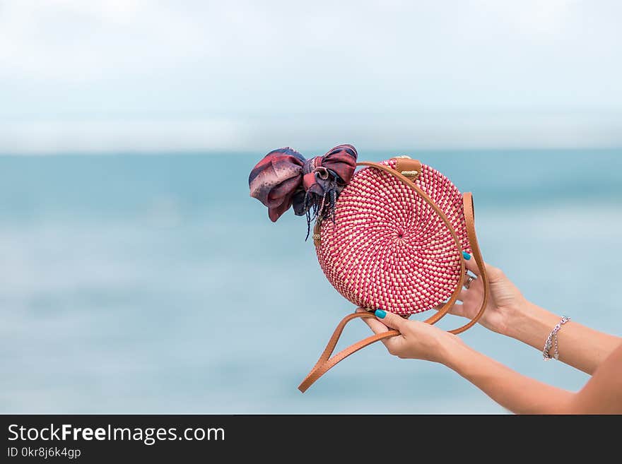 Selective Focus Photography of Person Holding Red and Brown Leather Crossbody Bag