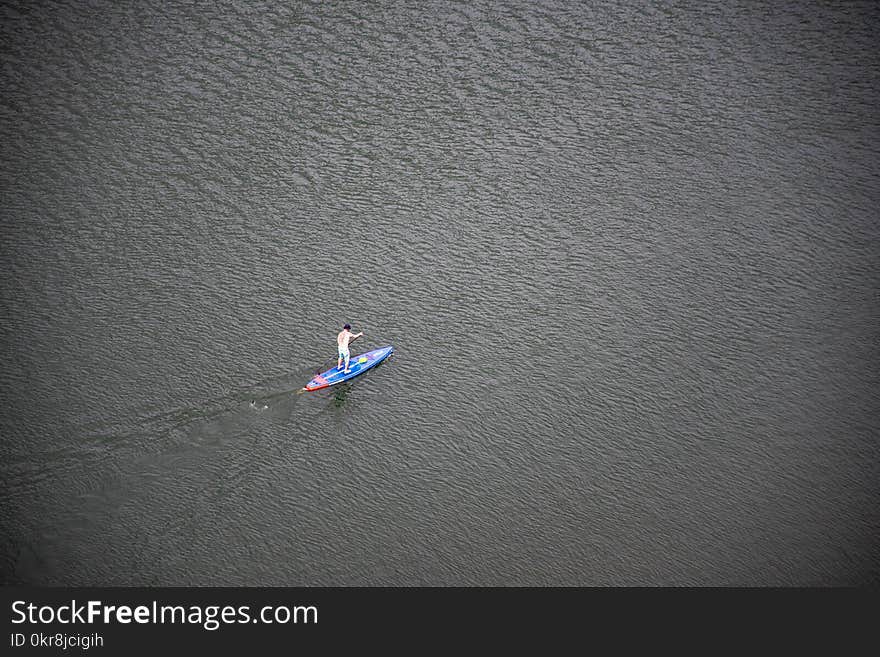 Person Riding Blue and Red Paddleboard on Water