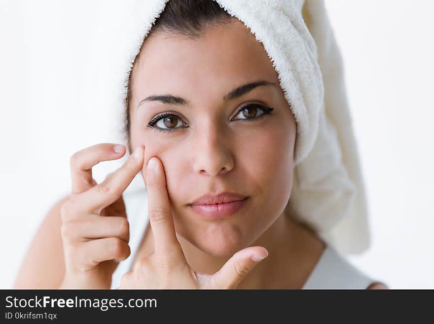 Portrait of beautiful young woman removing pimple from her face in a bathroom home.