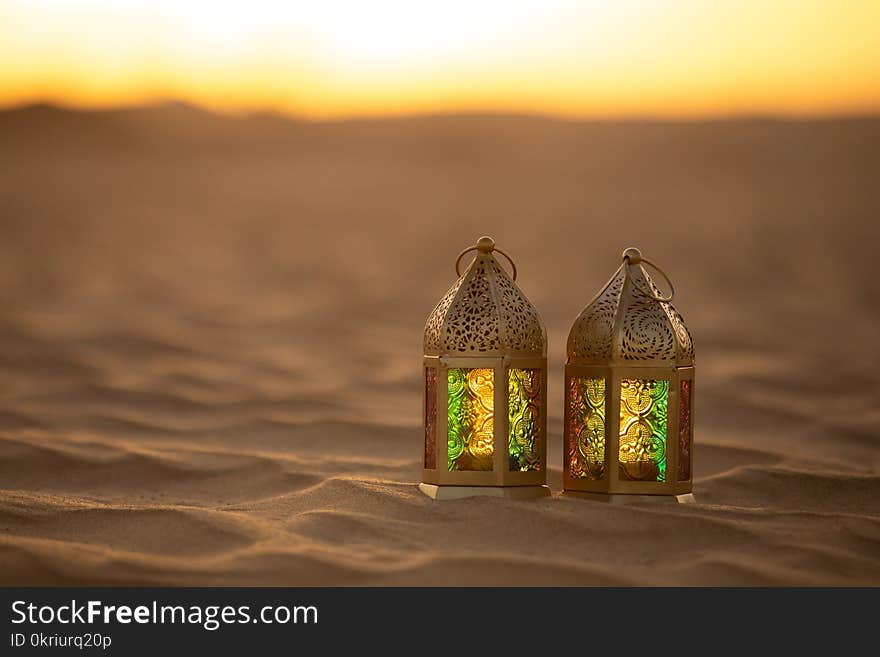 Traditional ornamental arabic lantern with a burning candle in desert during sunset. Festivel greeting card for Ramadan Kareem and Ramadan Mubarak. Dubai, UAE. Traditional ornamental arabic lantern with a burning candle in desert during sunset. Festivel greeting card for Ramadan Kareem and Ramadan Mubarak. Dubai, UAE.