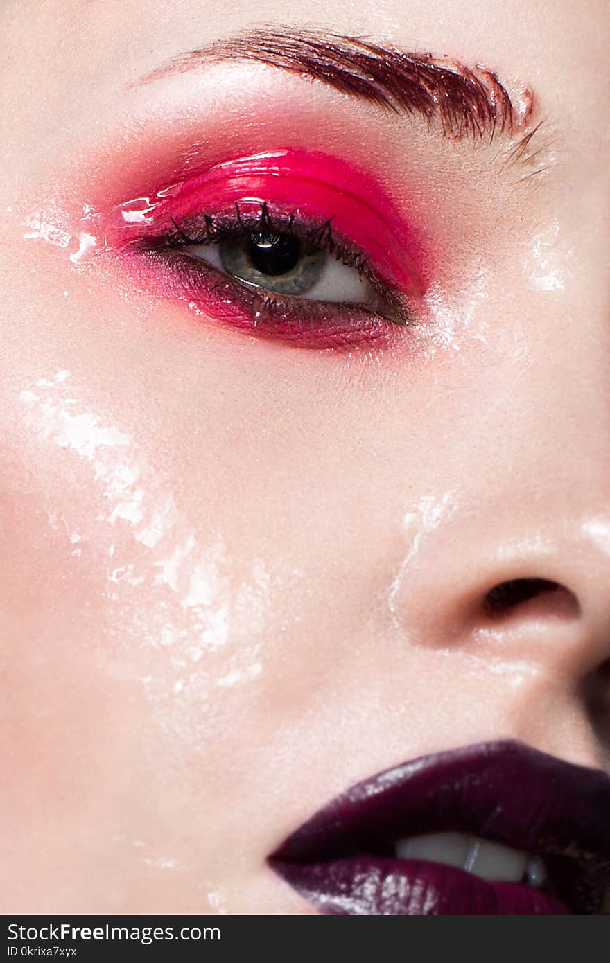 Young girl with bright red creative make-up. A beautiful model with wet skin and lips of the color of Marsala. Shining skin. A closeup portrait. Beauty of the face.