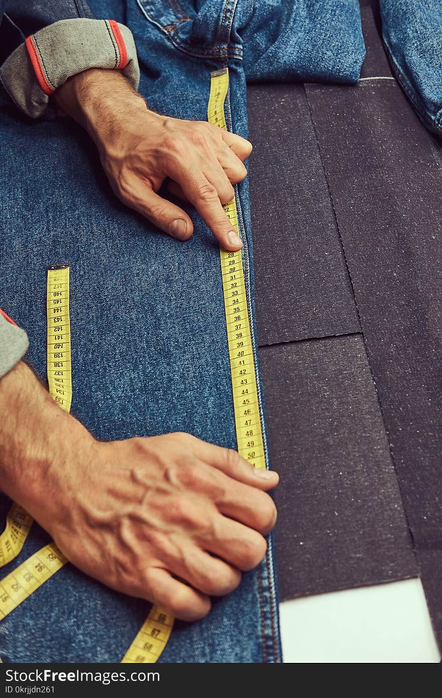 Cropped Image Of A Tailor Makes Measurements Of Jeans Cloth Samples At Sewing Workshop.