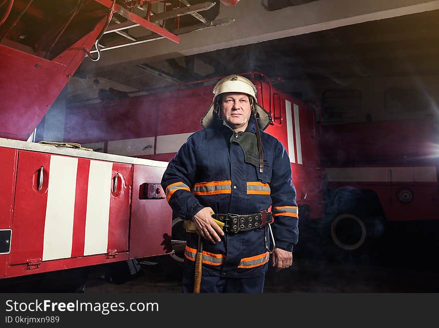 Fireman firefighter in action standing near a firetruck. Emergency safety. Protection, rescue from danger.