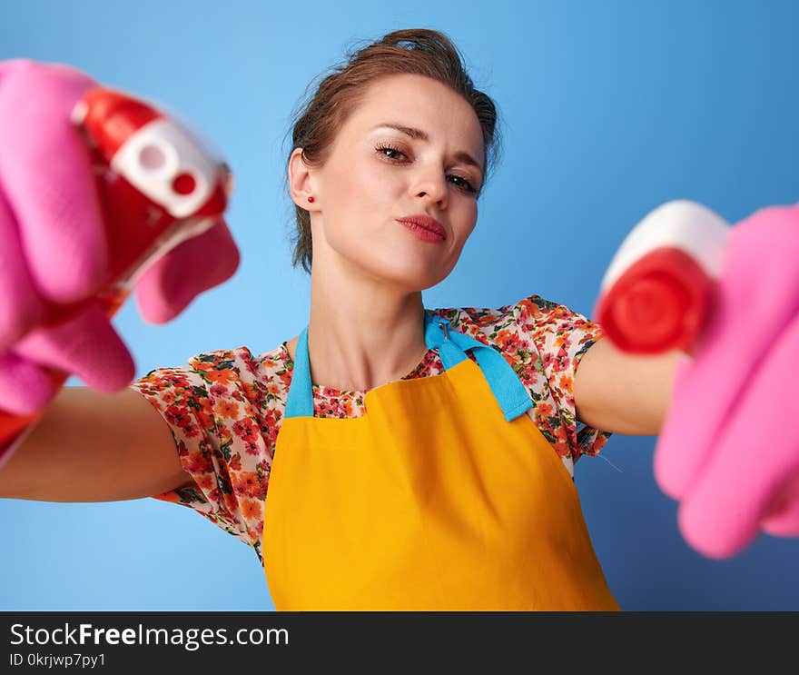 Big cleaning time. cool young housewife with rubber gloves using bottles of cleaning detergent as guns isolated on blue. Big cleaning time. cool young housewife with rubber gloves using bottles of cleaning detergent as guns isolated on blue