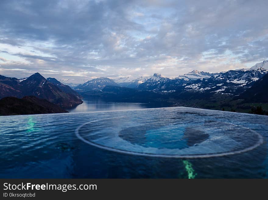 River Surrounded by Mountains Under White Clouds