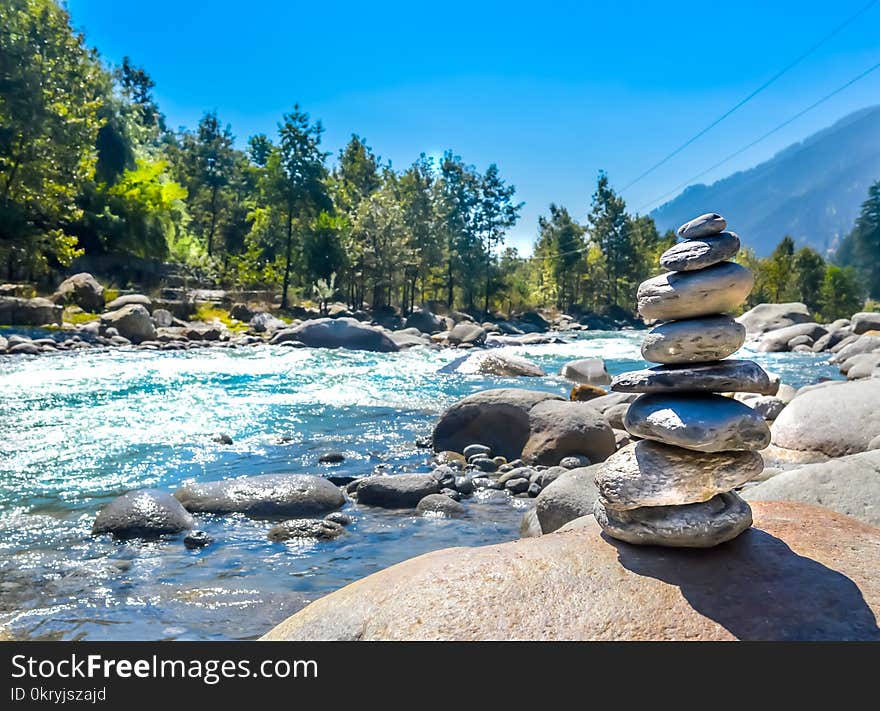 Balance and wellness retro spa concept, inspiration, zen-like and wellbeing tranquil composition. Close-up of white pebbles stack balanced stones on the rocky shore over near river side.