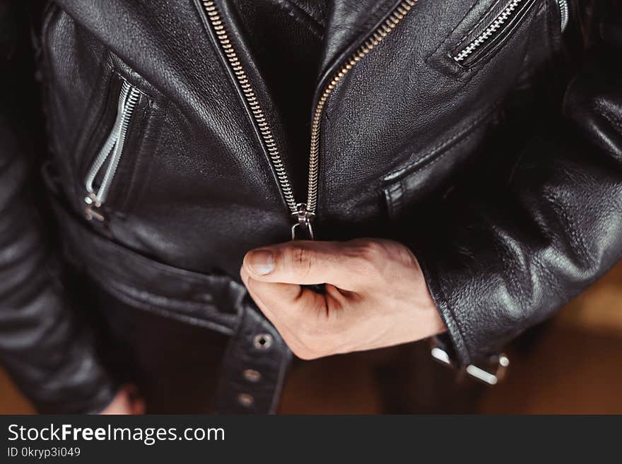 Fastens the lock on a Black leather jacket with zipper close-up. Fastens the lock on a Black leather jacket with zipper close-up