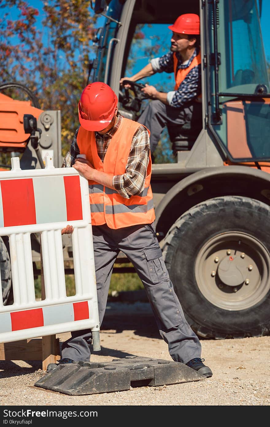 Worker setting up earthworks construction site erecting fence