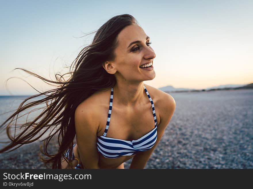 Woman on a pebble beach after sunset enjoying the breeze