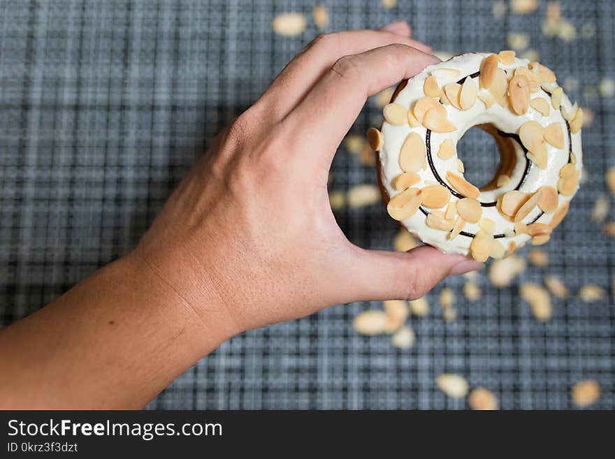 Man`s hand hold a White chocolate Donut with Almond sliced