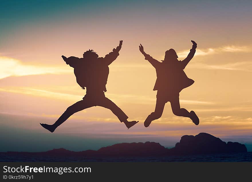 Silhouette young couple a jump on the sea beach at sunset concept of long-awaited vacation. Silhouette young couple a jump on the sea beach at sunset concept of long-awaited vacation