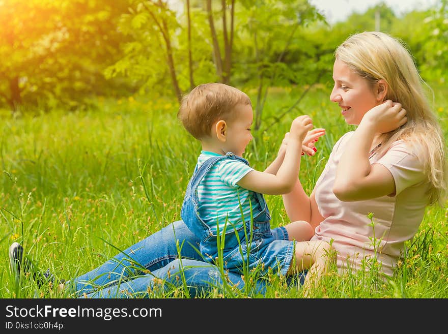 Mother and child in nature in the Park, resting on the green grass in Sunny weather, happy family. Mother and child in nature in the Park, resting on the green grass in Sunny weather, happy family