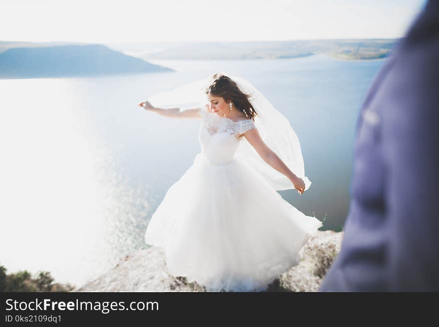 Elegant stylish happy wedding couple, bride, gorgeous groom on the background of sea and sky.