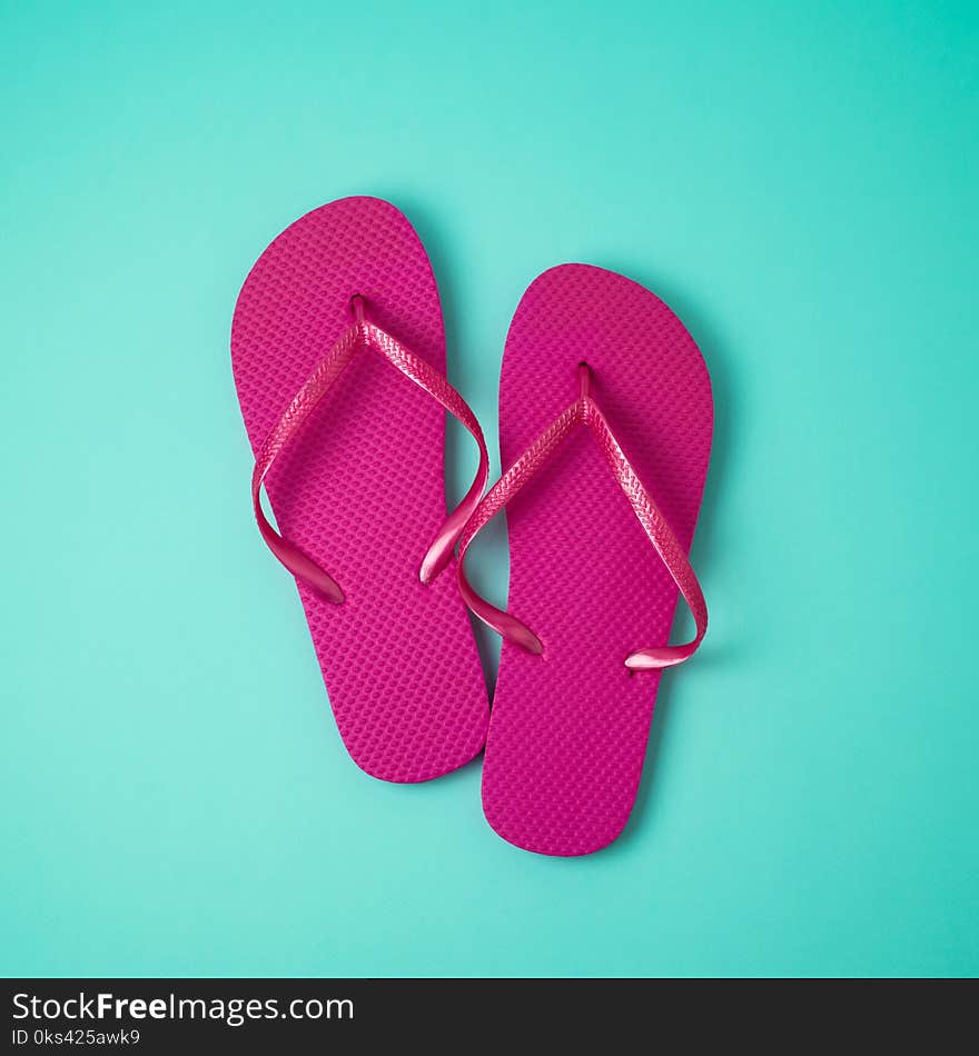 Pink flip flops over blue background.