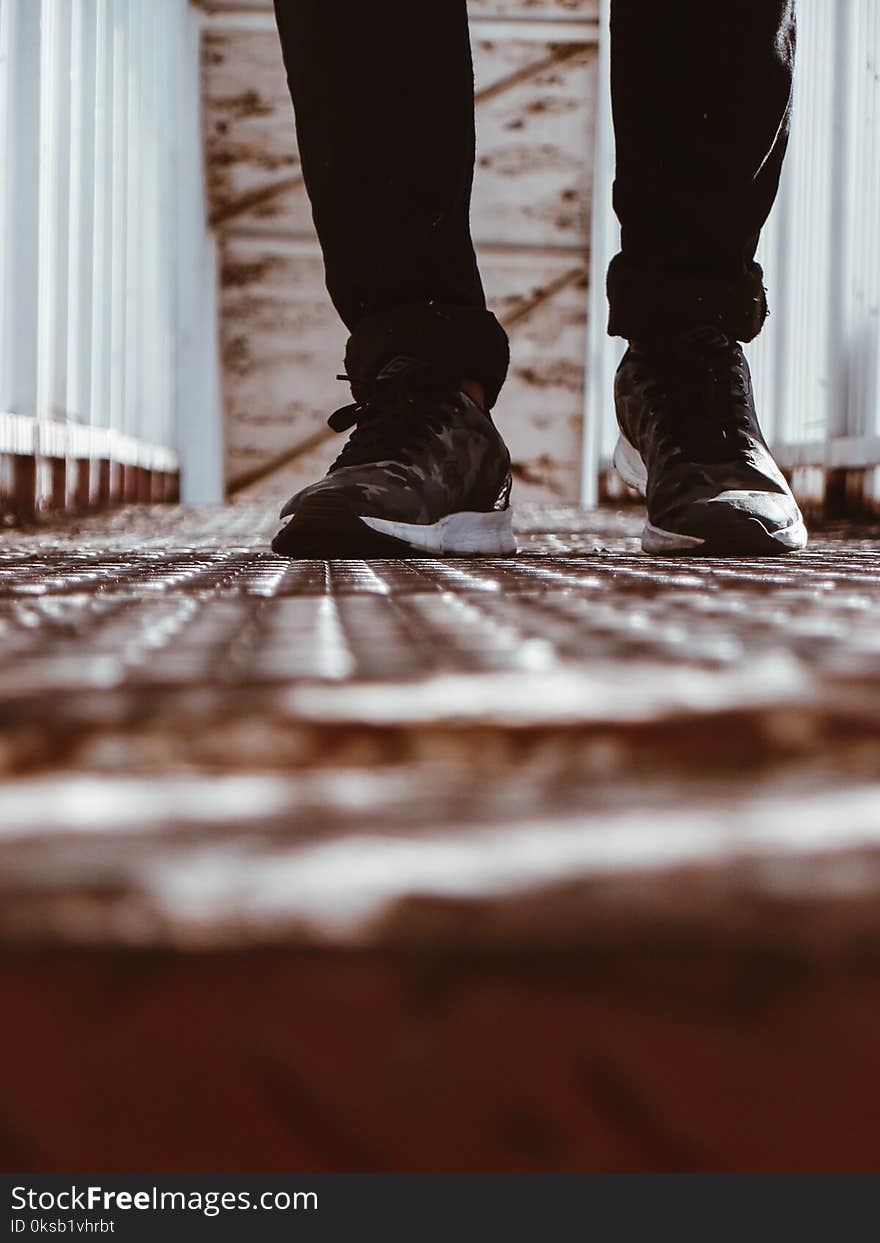 Person in Black-and-white Shoes Standing on Brown Metal Floor