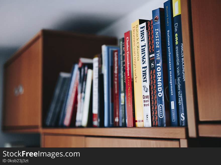 Assorted Books on Brown Wooden Shelf