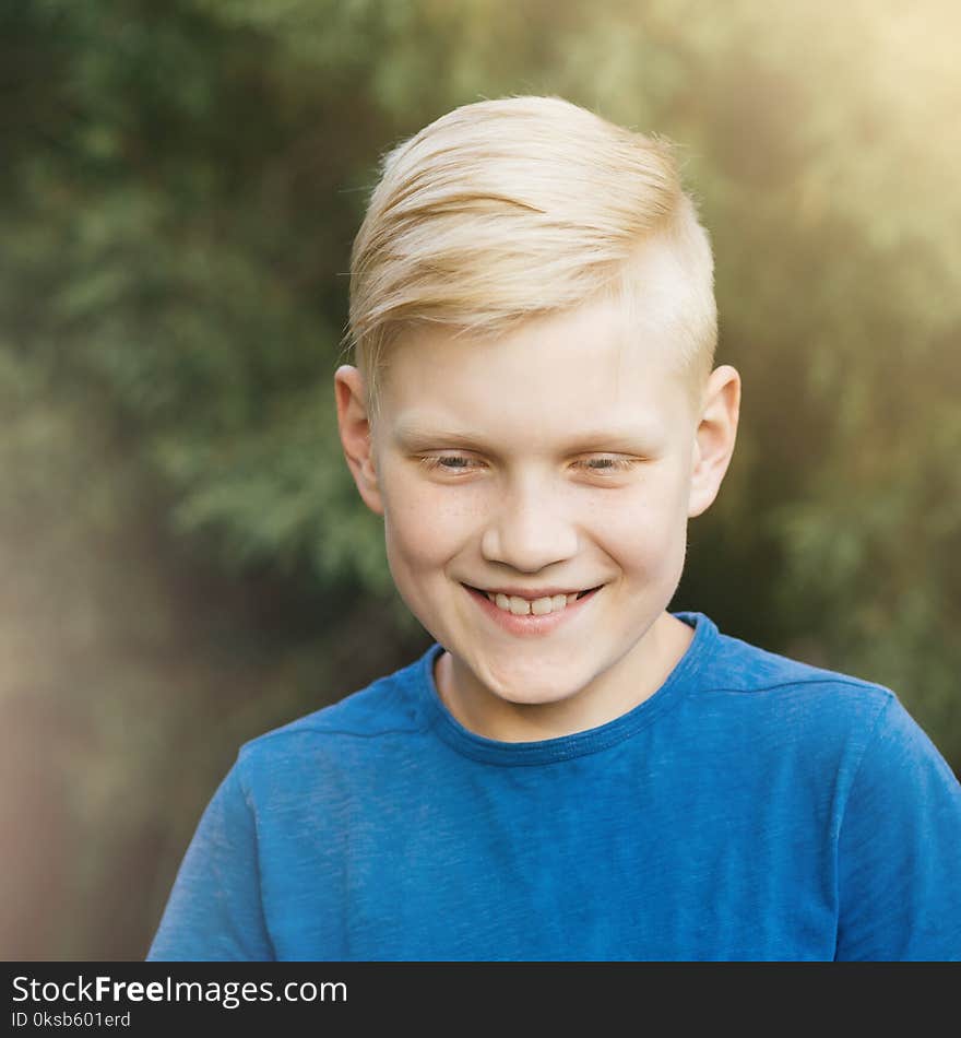 Blond teenager in blue t-shirt smiling. Sincere laughter, a living emotion. Candid boy. Blond teenager in blue t-shirt smiling. Sincere laughter, a living emotion. Candid boy.