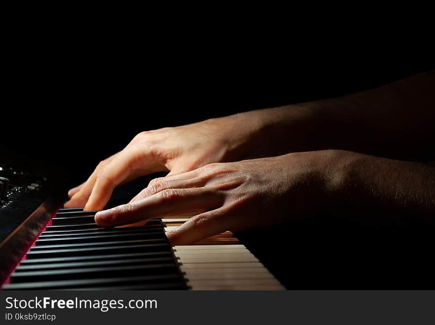 Hands playing a piano keyboard with black background. Hands playing a piano keyboard with black background