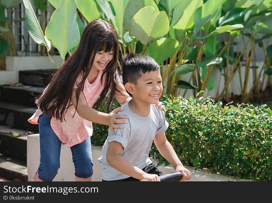 Happy young kid having fun with sister riding a bike