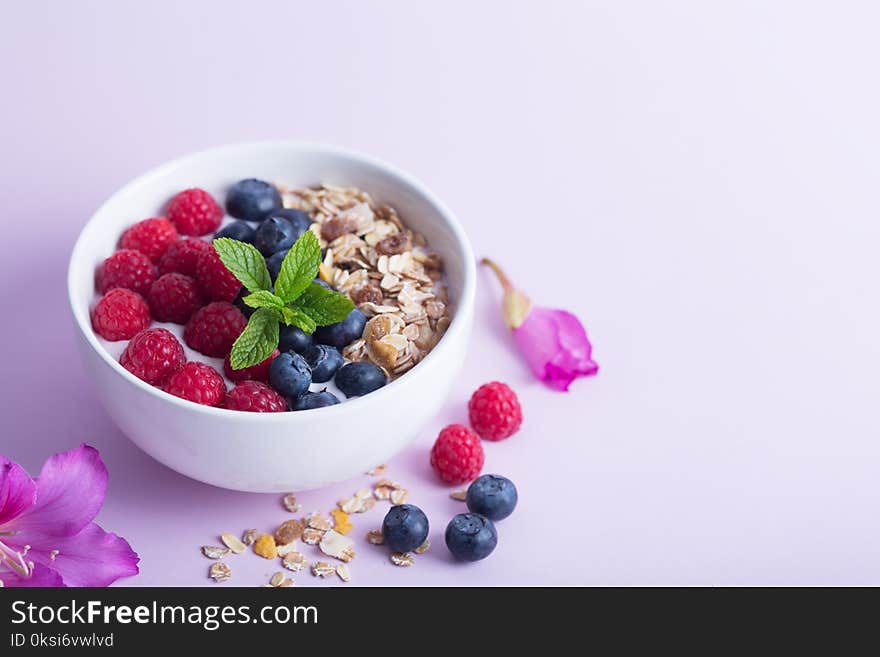 Smoothie bowl with yogurt, fresh berries and cereal on the pink background