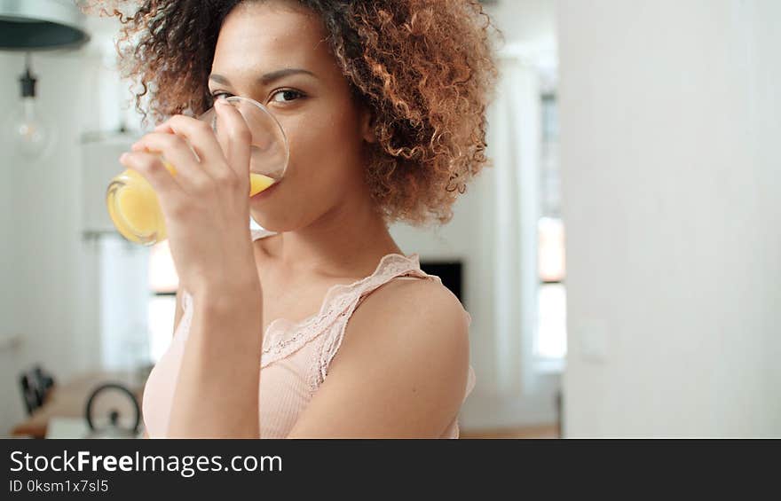 Happy mixed race young cheerful woman with smoothie at home. Happy mixed race young cheerful woman with smoothie at home.