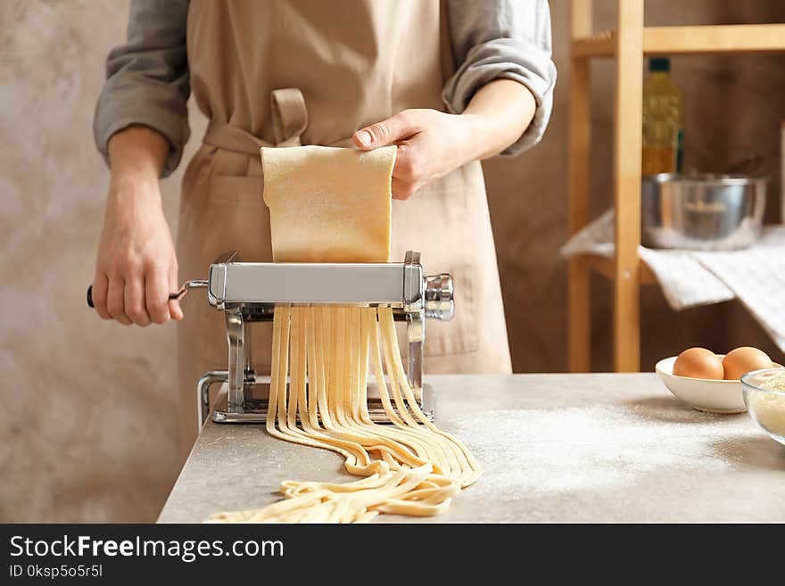 Young woman preparing noodles with pasta maker