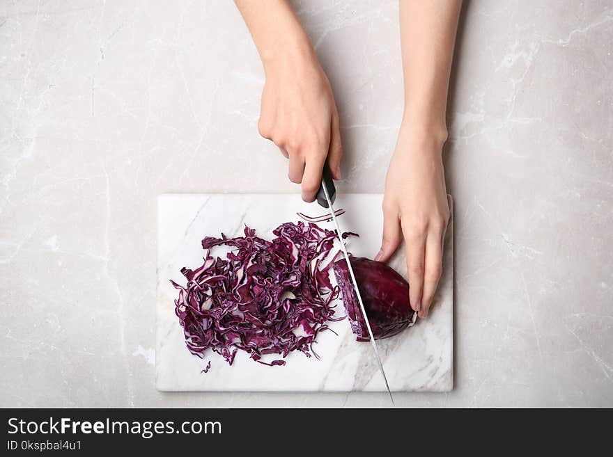 Woman cutting red cabbage on marble board, top view