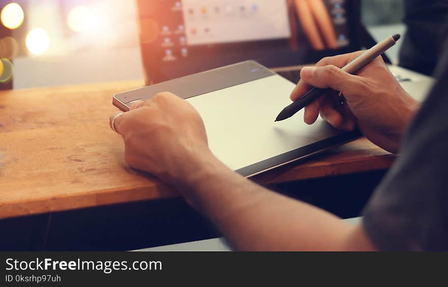 Designer with pen mouse in hand. Man with wirless digital pen drawing and writing on tablet board in office background.