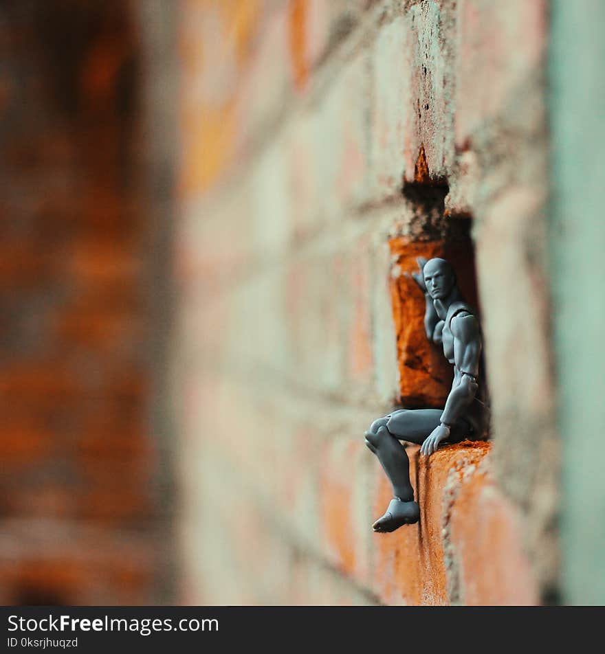 Action Figure on a Hole of Brick Wall