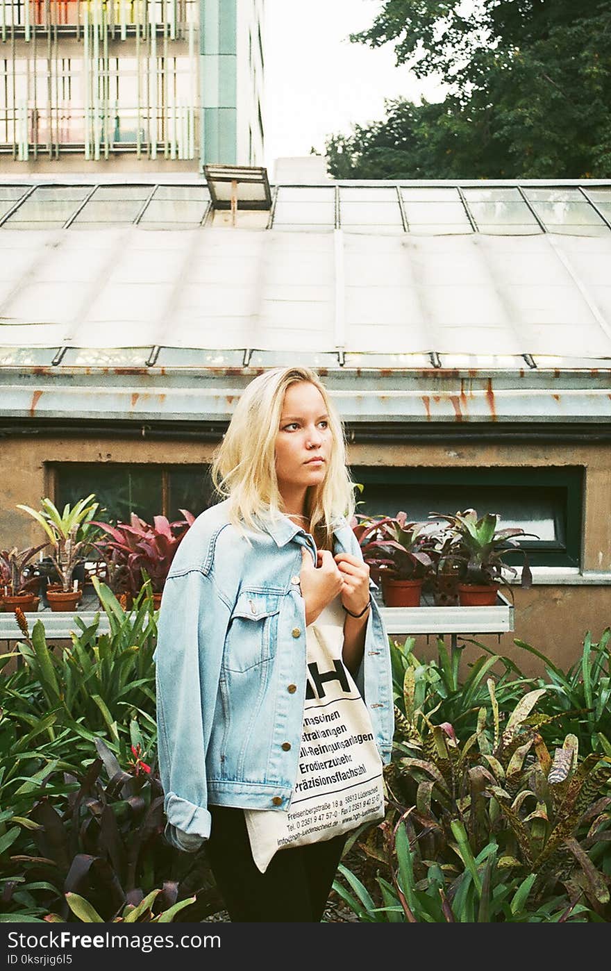 Woman Wearing White Shirt and Denim Jacket Standing Near House