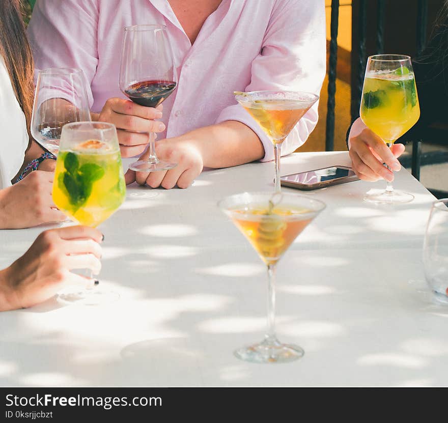 Clear Cocktail Glass on Top of White Wooden Table